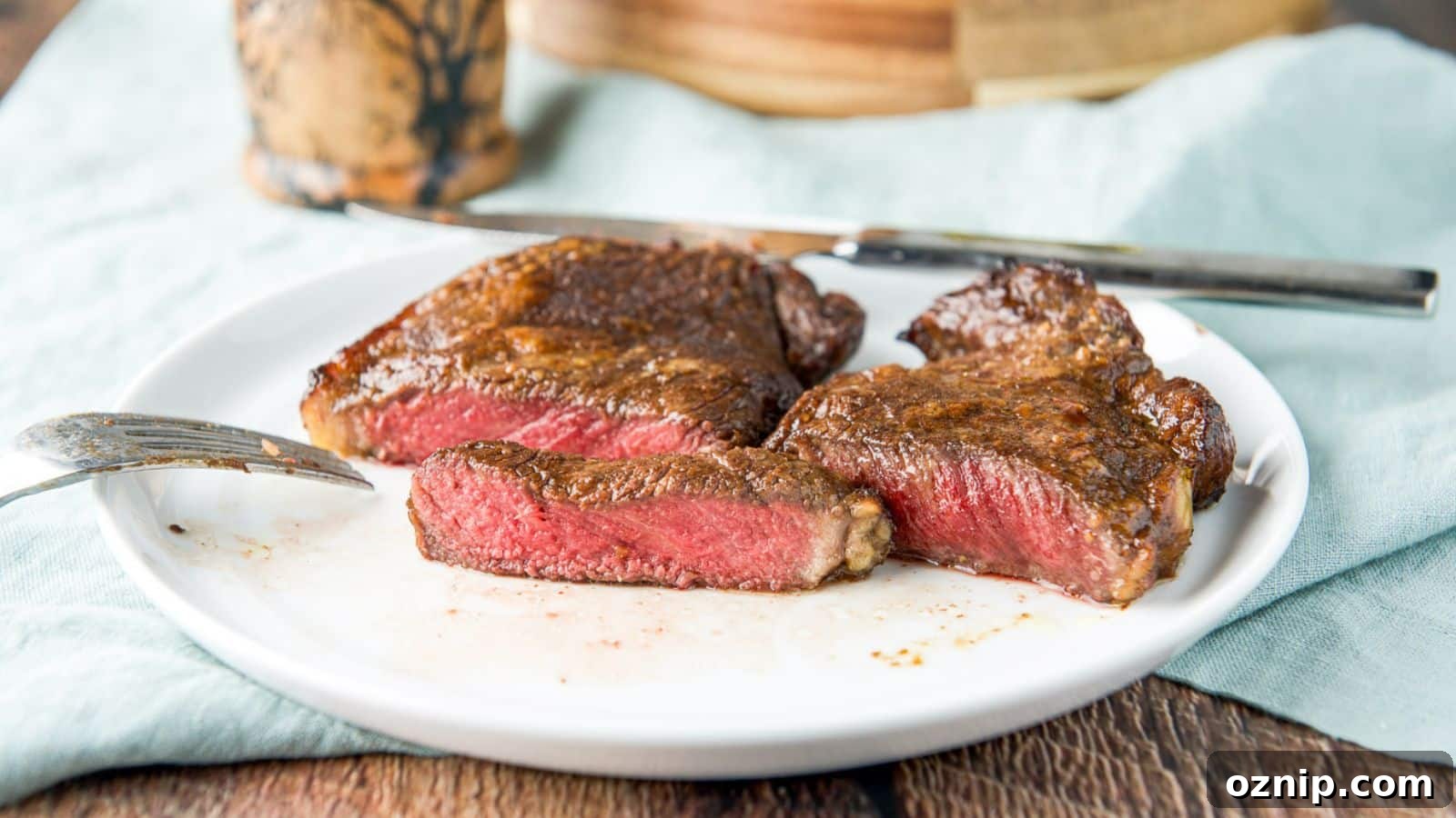A white plate with a medium rare steak cut in half and a piece cut out of it