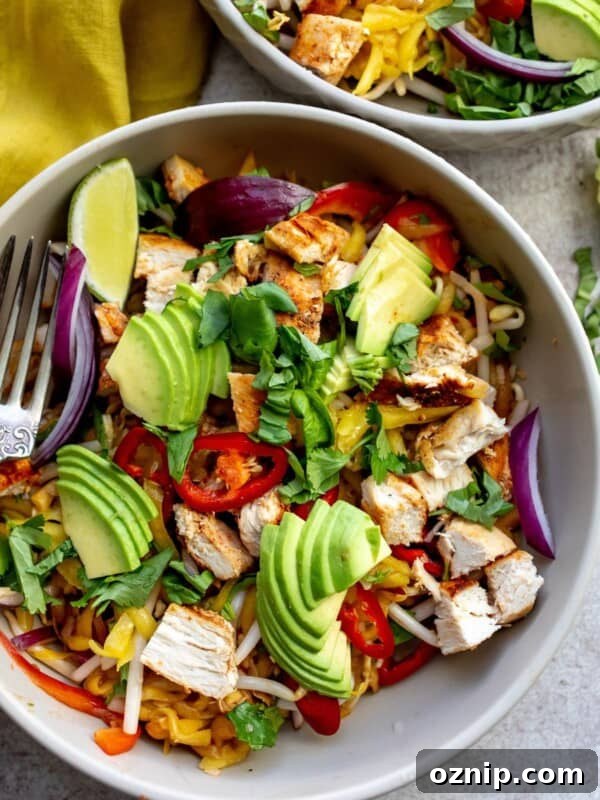 Two grey bowls with thai mango salad and a fork in the bowl on the table.