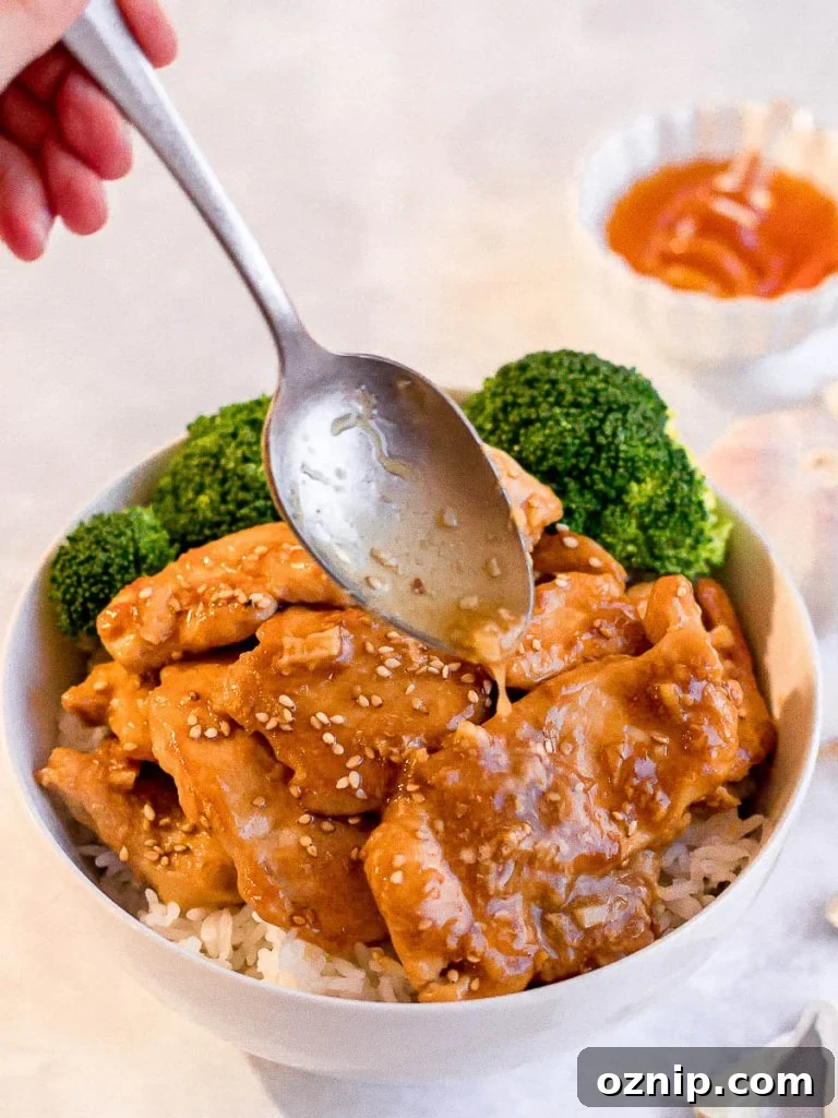 spoon drizzling honey garlic sauce on honey garlic chicken stir fry with steamed broccoli and rice