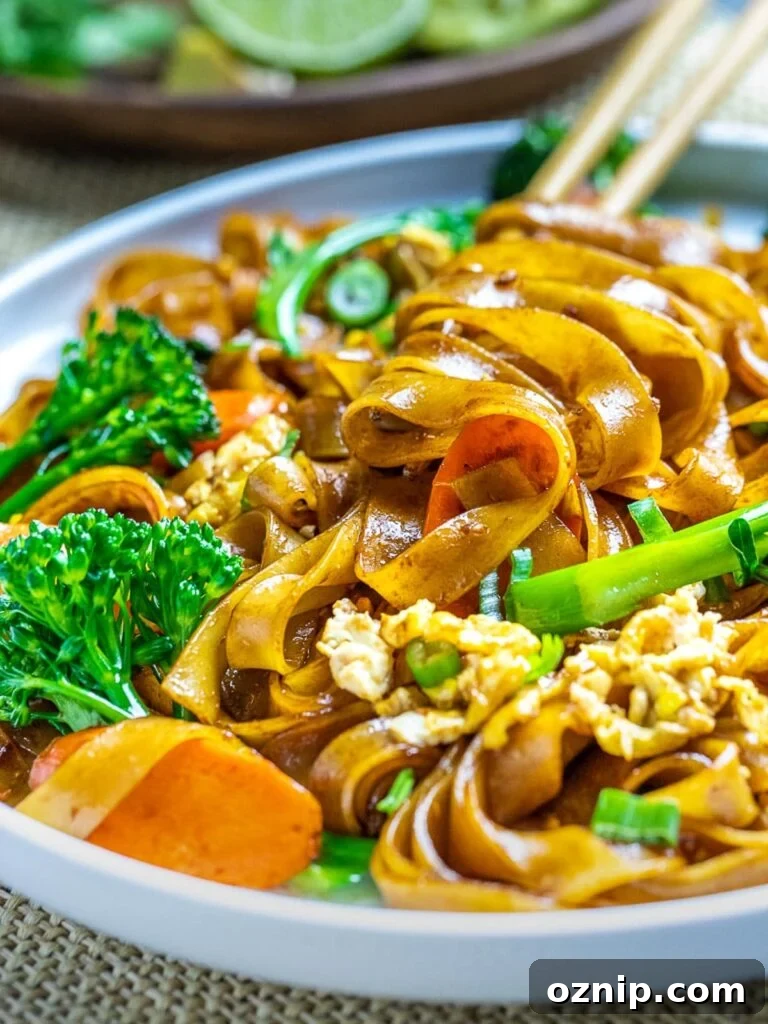 pad see ew thai noodles with vegetables on white plate