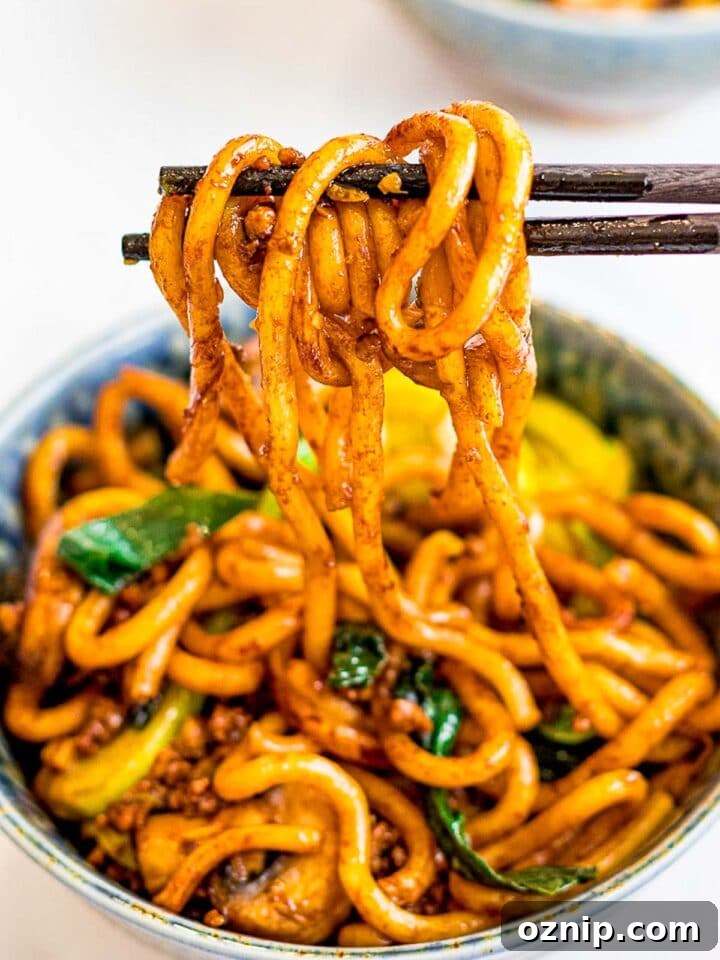a bowl of yaki udon, stir fried udon noodles held by chopsticks