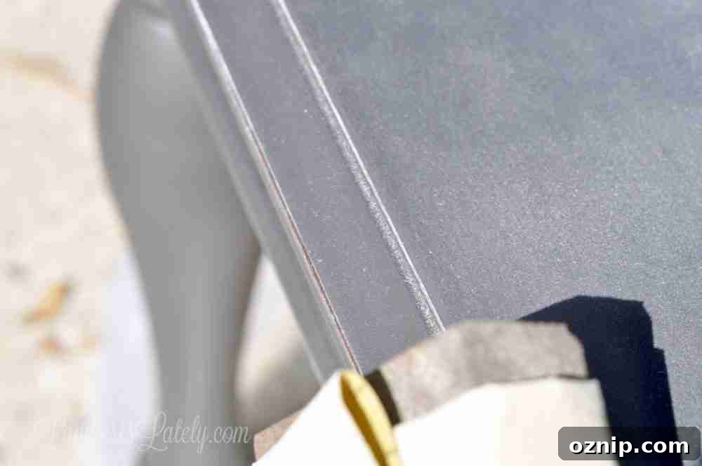 sanding the edge of a gray painted end table.