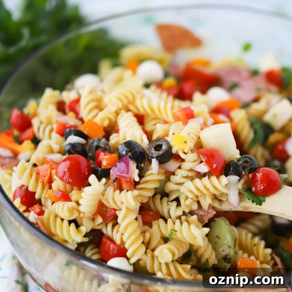 A glass serving bowl full of pasta salad.