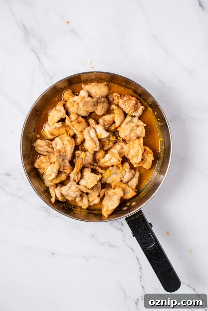 Close-up of glazed orange chicken with sesame seeds.