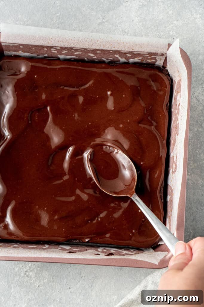 Spreading the ganache over the top of the brownies.