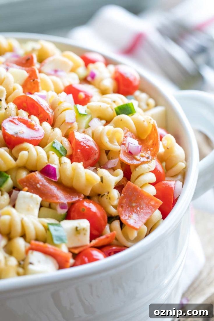 Top 10 Recipes of 2021: Most Popular Dishes Revealed 3 Closeup of a white serving bowl full of Italian pasta salad with forks and a red-striped cloth in the background.