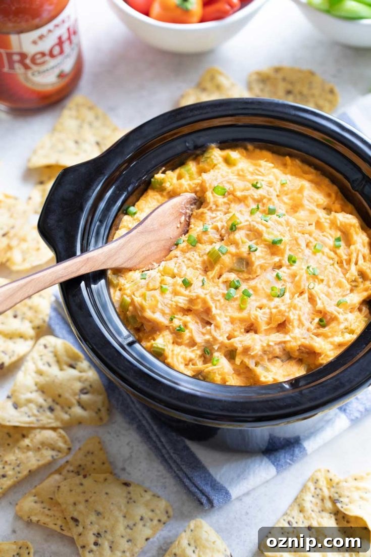 Top 10 Recipes of 2021: Most Popular Dishes Revealed 4 Cooked buffalo-style chicken dip in a crockpot insert with dippers nearby.