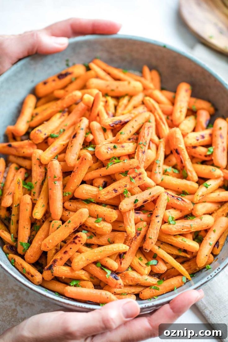 Top 10 Recipes of 2021: Most Popular Dishes Revealed 5 Two hands holding a blue serving bowl piled with roasted carrots, fresh from the oven.