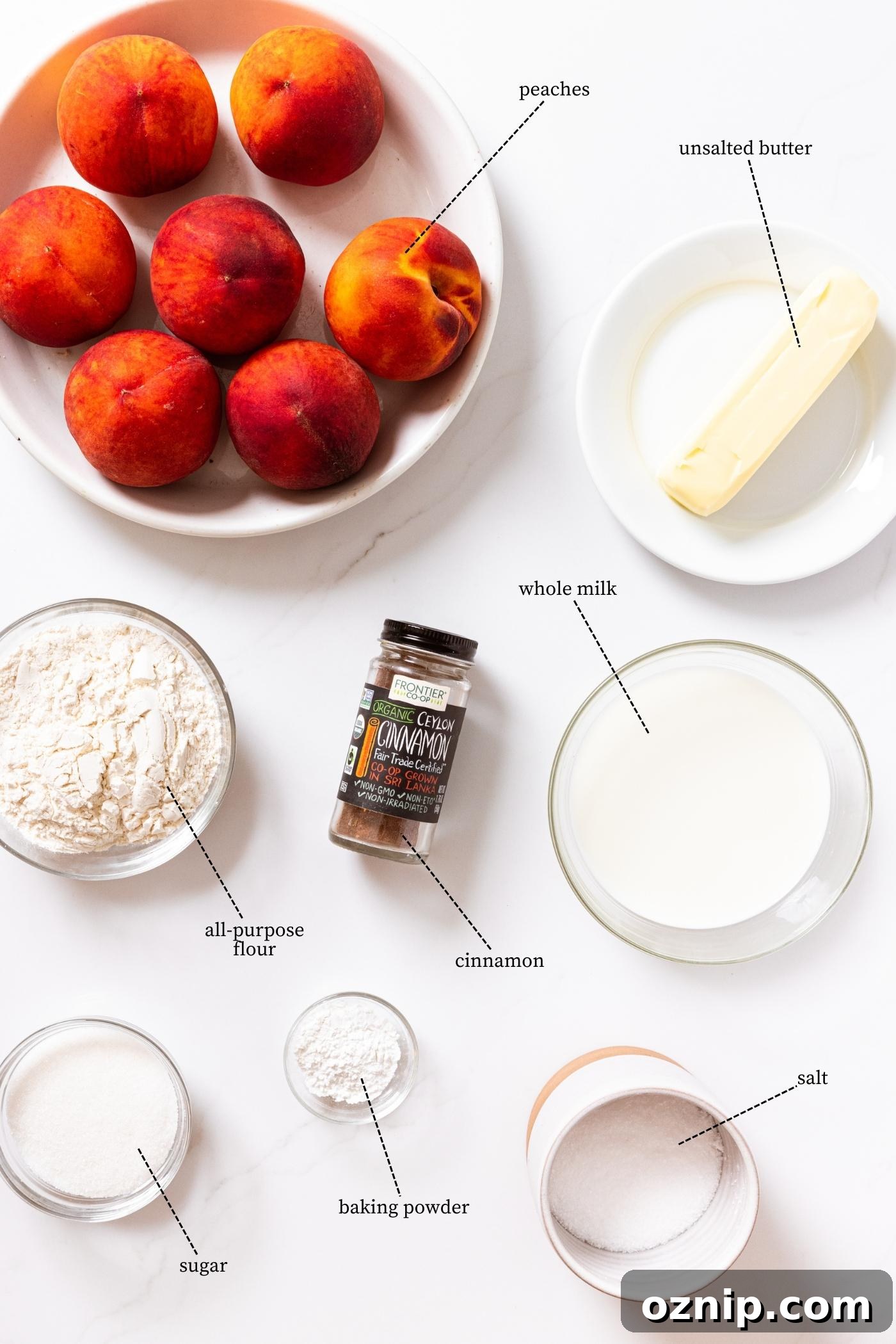 White countertop filled with ingredients needed to make peach cobbler including flour, peaches, butter, cinnamon, and more.