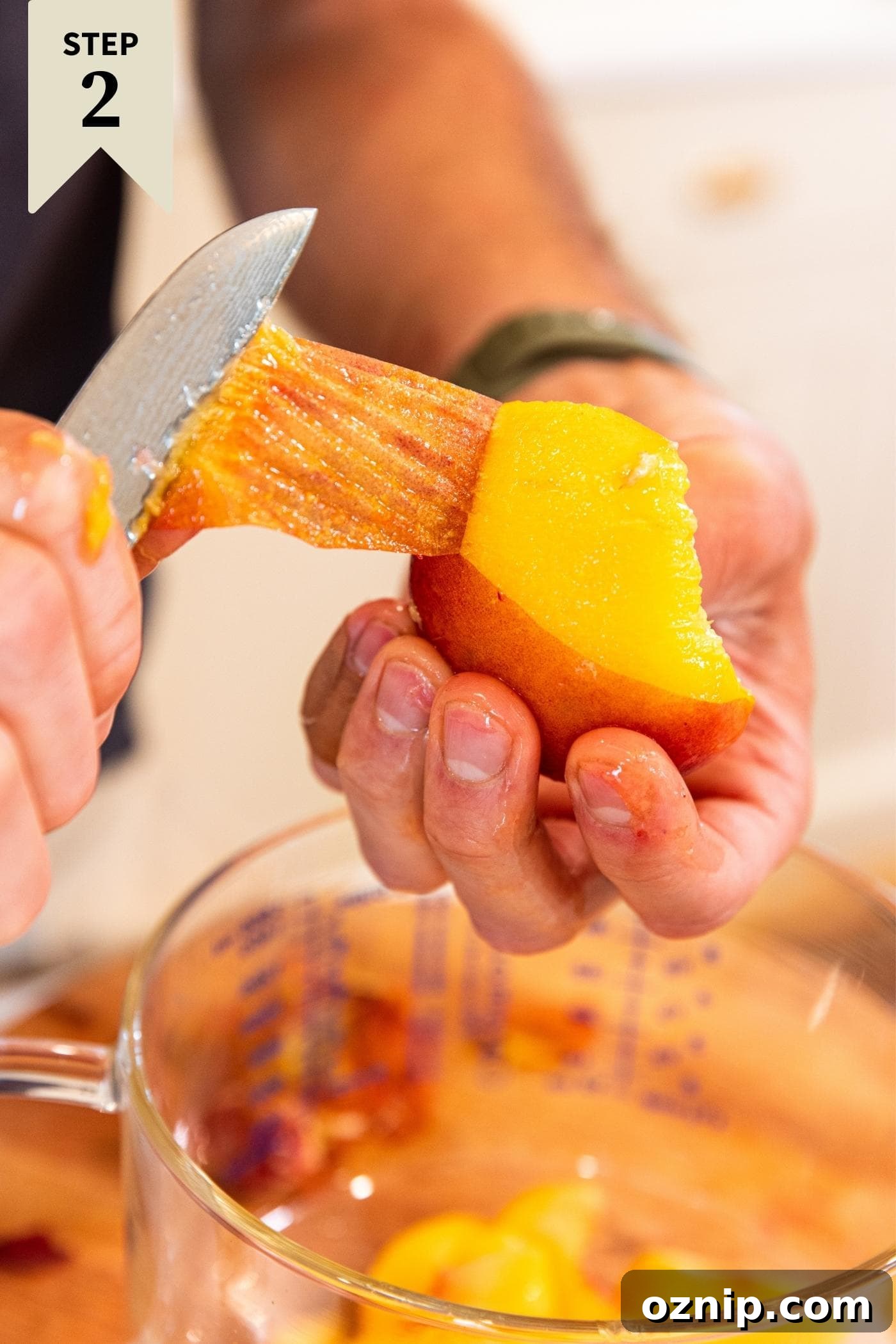 Hand holding knife pulling the skin off a peach before slicing it up.