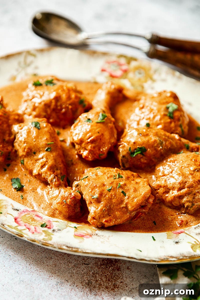 A side view of chicken in sauce on a platter