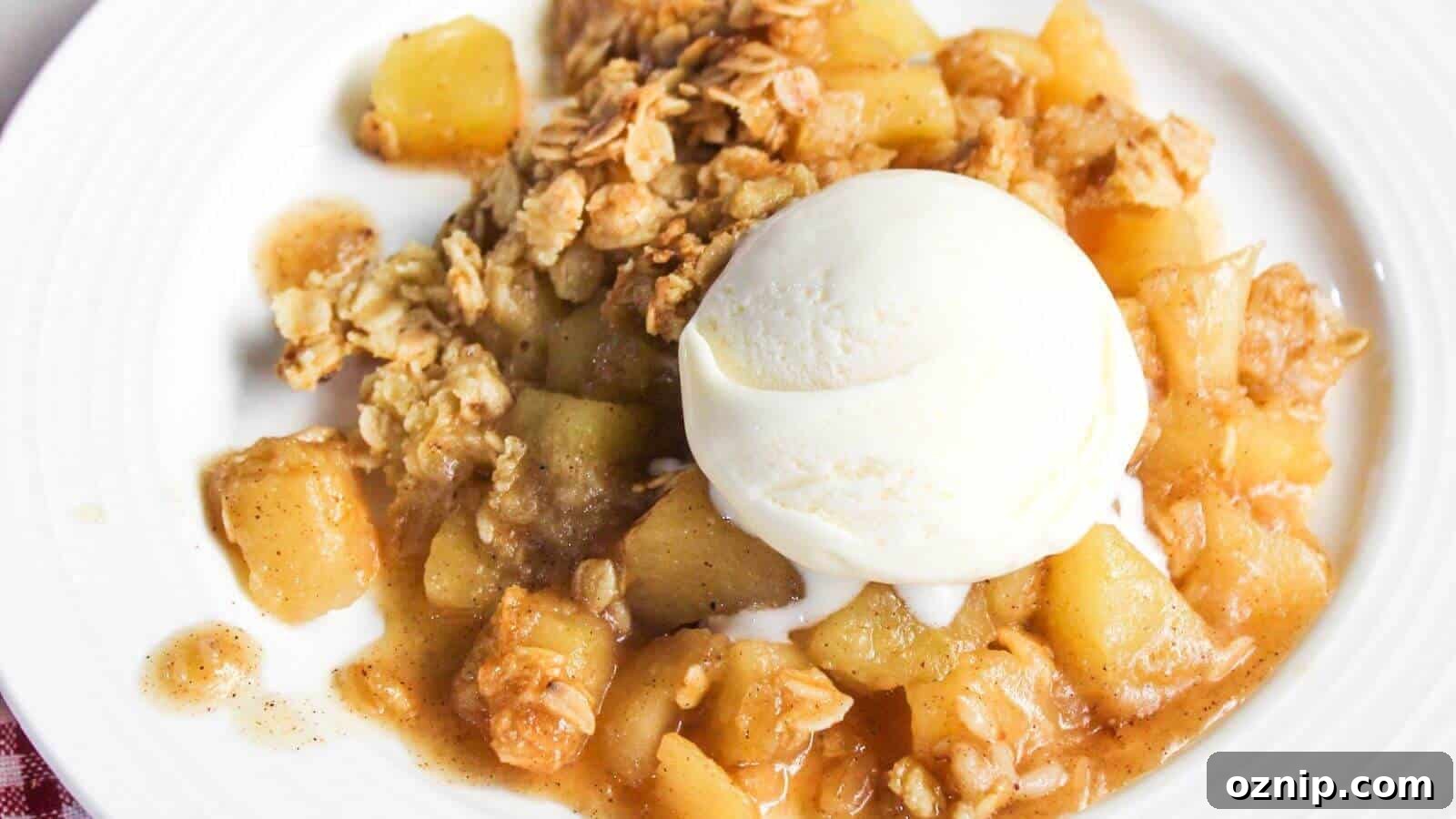 A plate of apple crumble topped with a scoop of vanilla ice cream. The crumble includes chunks of baked apples and a crumbly oat mixture.