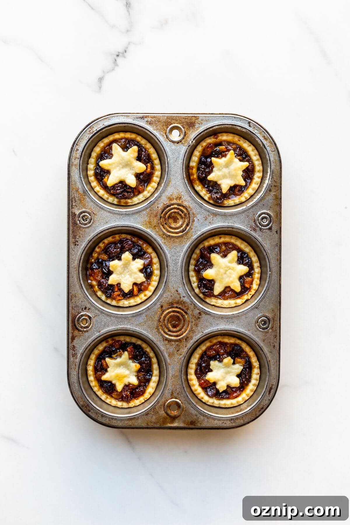Freshly baked mincemeat tarts in a muffin tin, ready to unmould and serve.