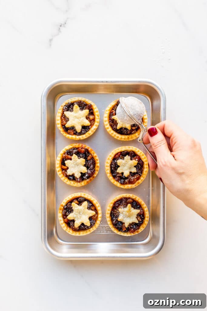 Sprinkling powdered sugar over freshly baked mince pies.