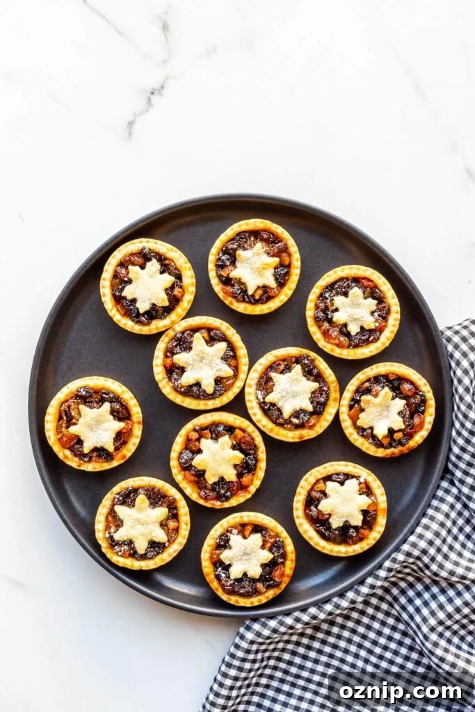 A black plate with mince pies and a black and white checkered linen.