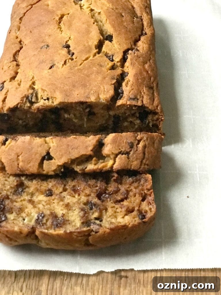 High angle photo of a loaf of healthy banana bread on a parchment lined wooden surface