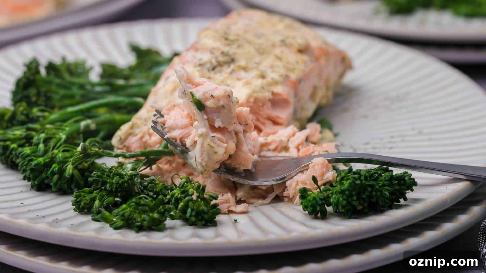 Plate with baked salmon, garnished with herbs, served alongside steamed broccolini.