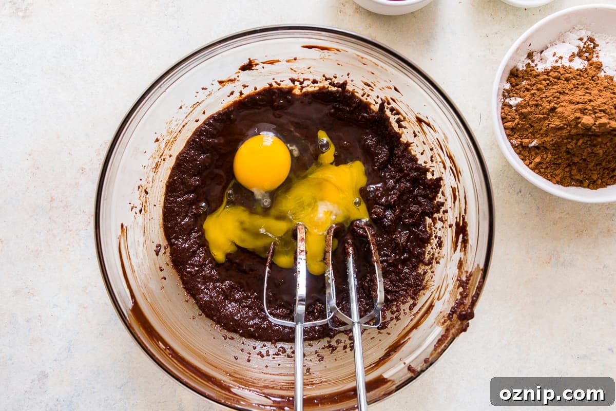 eggs added to brownie batter in a glass bowl