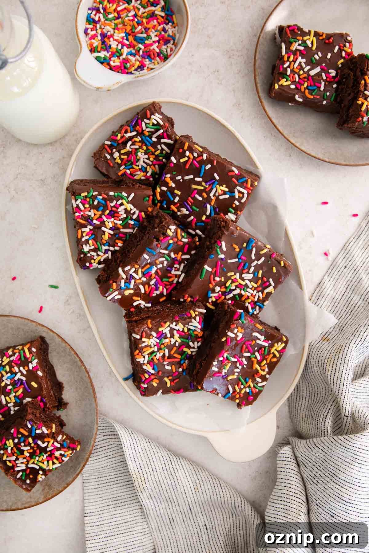 Fudgy Gluten-Free Birthday Brownies Recipe 3 sliced brownies topped with fudge frosting and rainbow sprinkles on a platter.