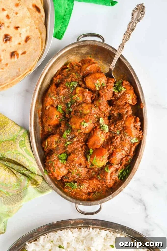 Restaurant Style Bombay Potatoes Recipe 3 Top down view of a brown potato curry with chapati in the left corner and basmati rice at the bottom
