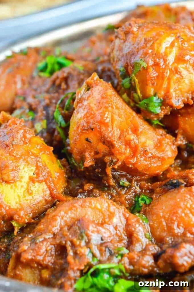 Restaurant Style Bombay Potatoes Recipe 4 Close up of halved potatoes in a brown curry sauce with fresh cilantro sprinkled on top