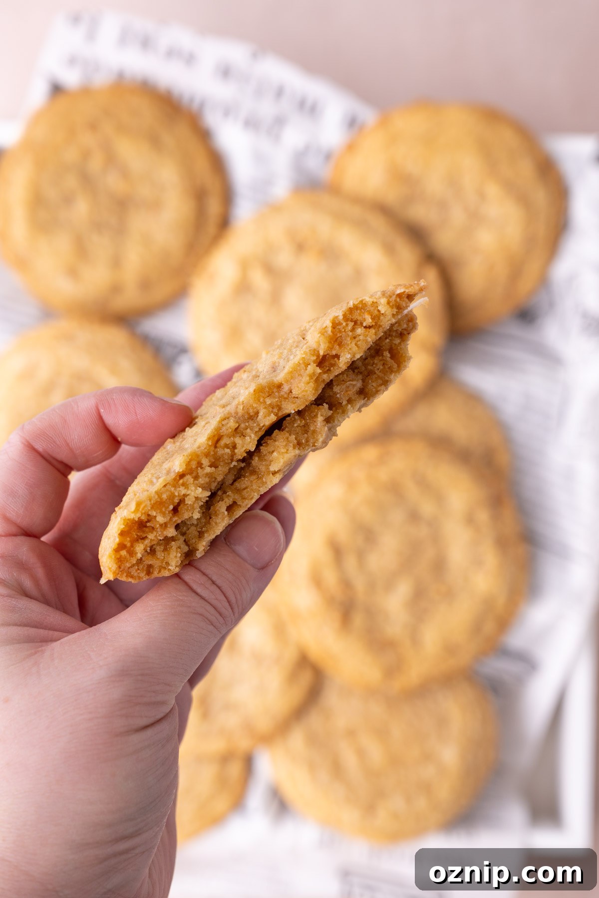 Buttery Crunch Cookies: Chewy Centers, Crispy Edges 12 Holding up a halved butter crunch cookie to the camera to see the texture of the inside.