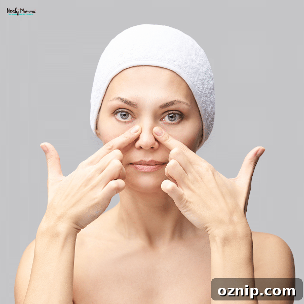 At Home Facial Exercises to Firm Skin and Smooth Fine Lines 3 A woman wearing a white towel on her head presses her fingers against the sides of her nose while performing a facial exercise.