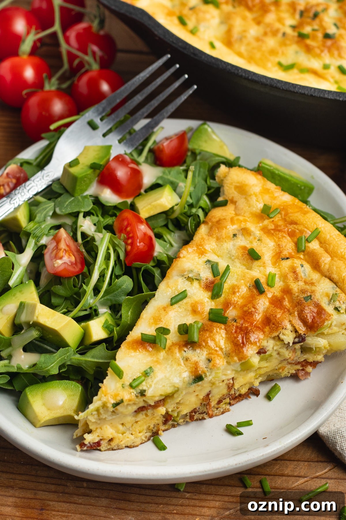 This is a picture of a plate with a slice of bacon and leek frittata with potatoes and a side salad.