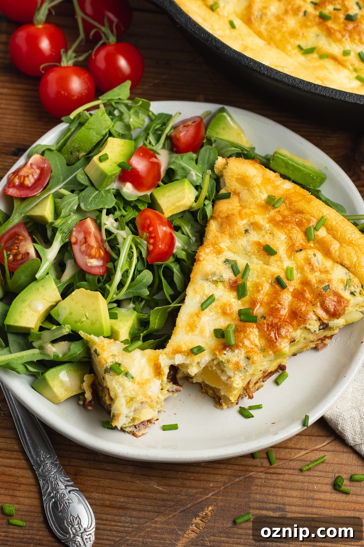 This is a picture of a plate with a slice of bacon leek frittata and a side salad.
