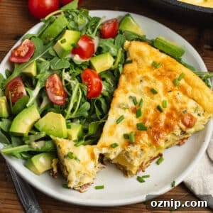 This is a square picture of the frittata on a plate with a side salad.