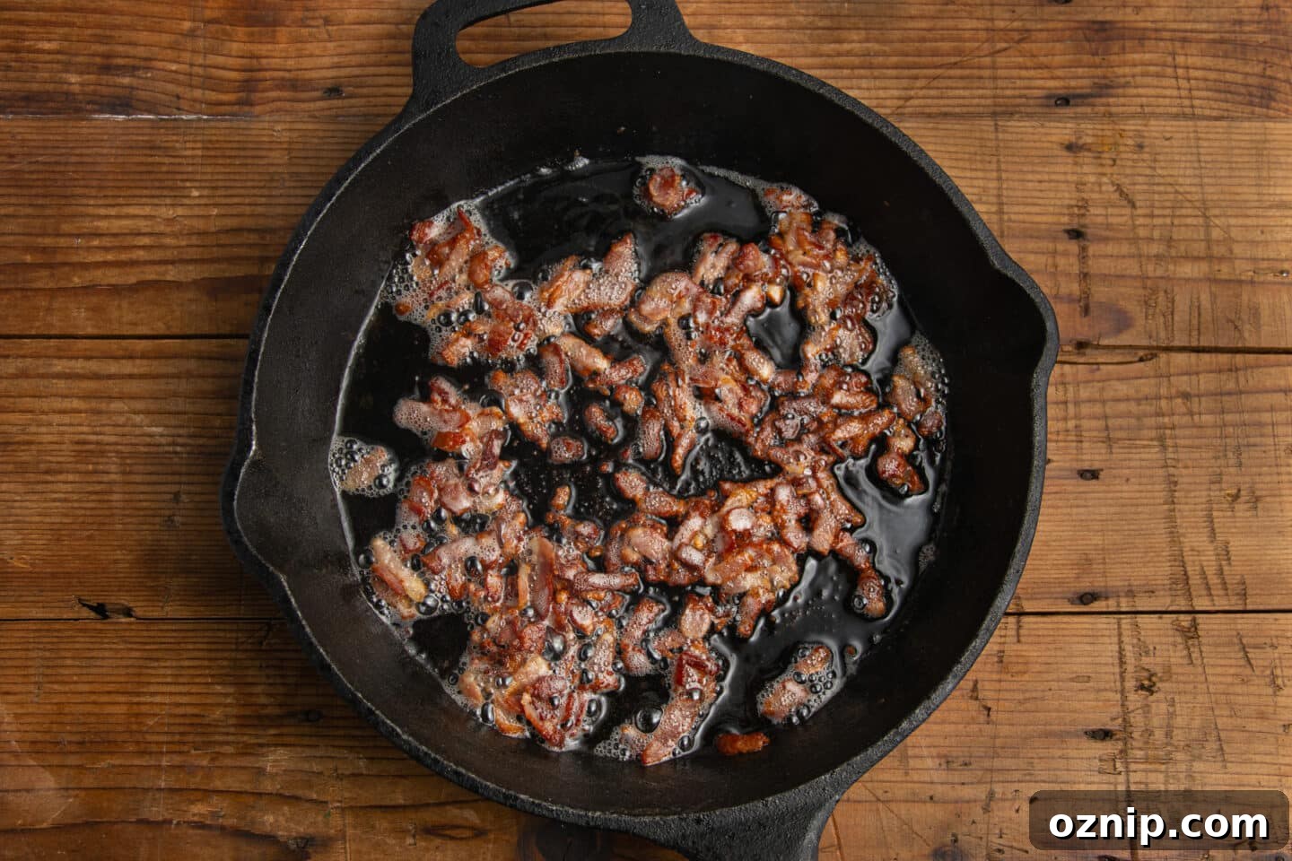 This is a picture of bacon being cooked in a cast iron skillet.