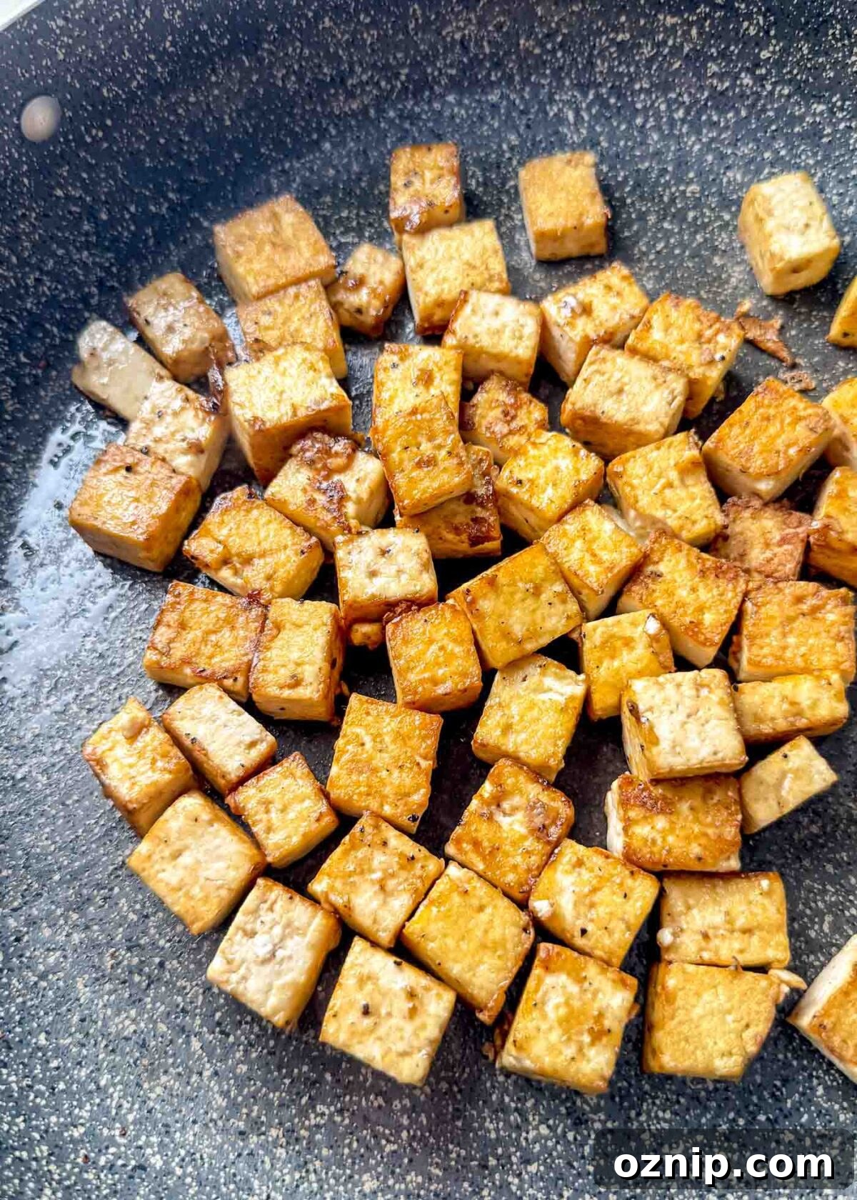 Sesame-Ginger Tofu Soba Noodles 6 Golden, crispy tofu cubes browning in a nonstick skillet with lightly caramelized edges.