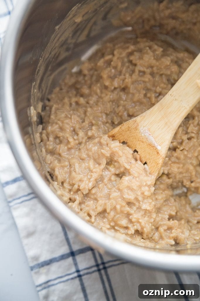 Creamy Instant Pot Brown Rice Pudding 5 The inner lining of an instant pot with creamy delicious brown rice pudding being stirred with a wooden spoon.