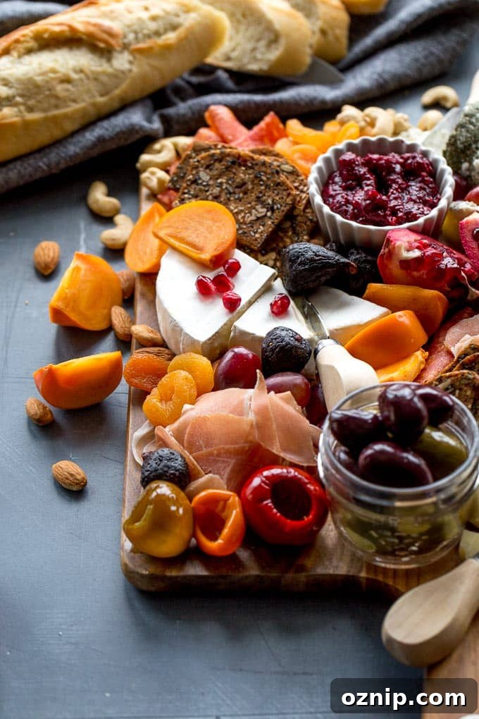 Side view of cheese, meats and fruit on a wooden board.