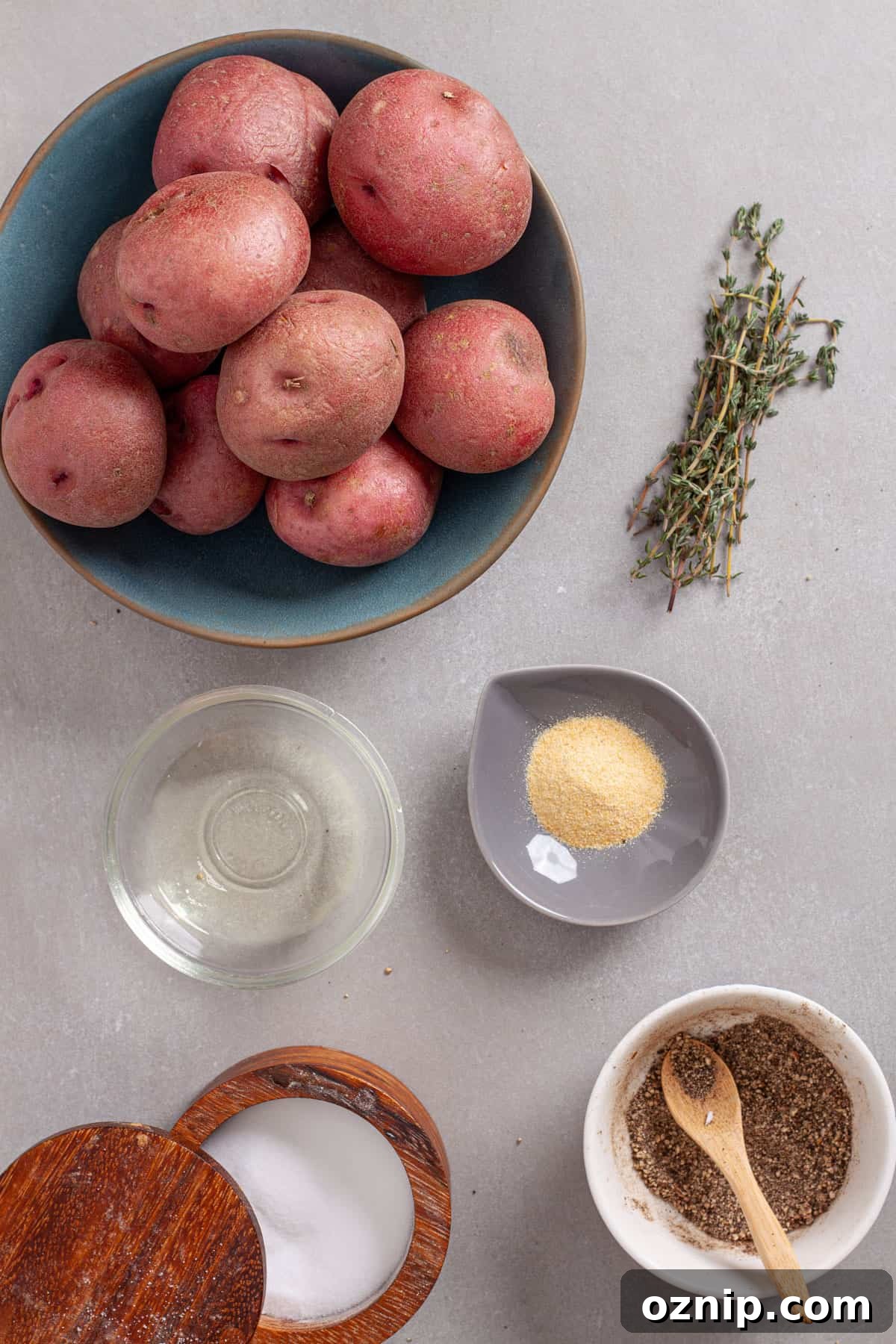 Ingredients for seasoned air fried red potatoes on a gray table.