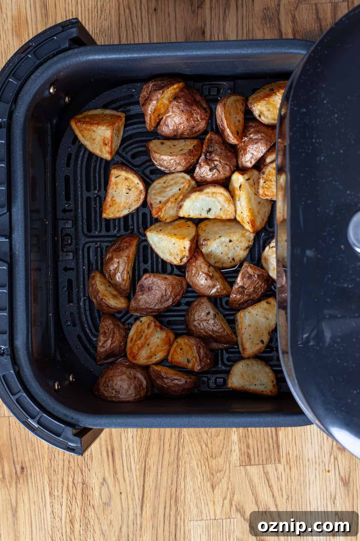 An air fryer basket with crispy seasoned small red potatoes.