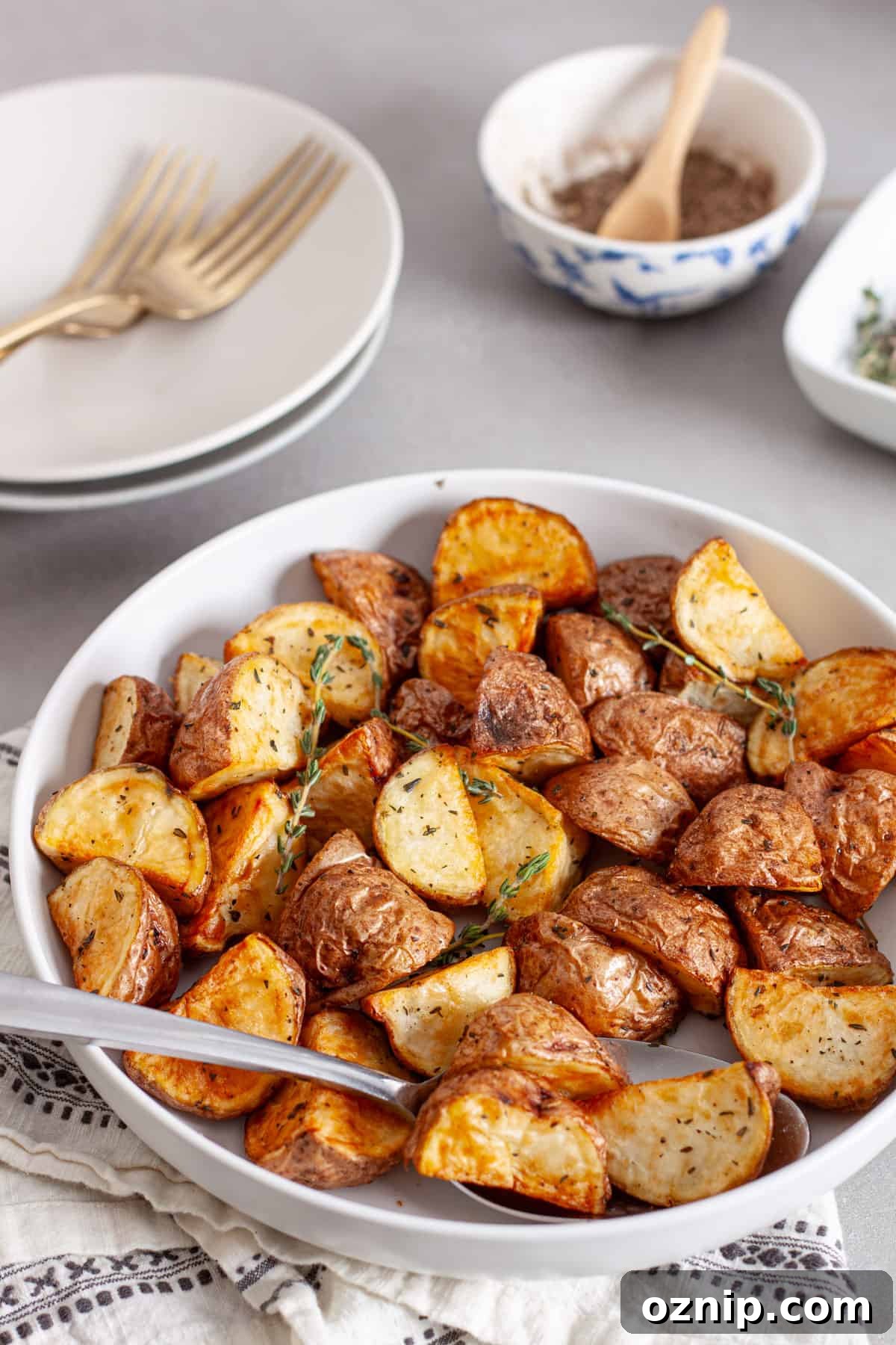 A serving bowl of air fryer red potatoes garnished with fresh thyme sprigs.