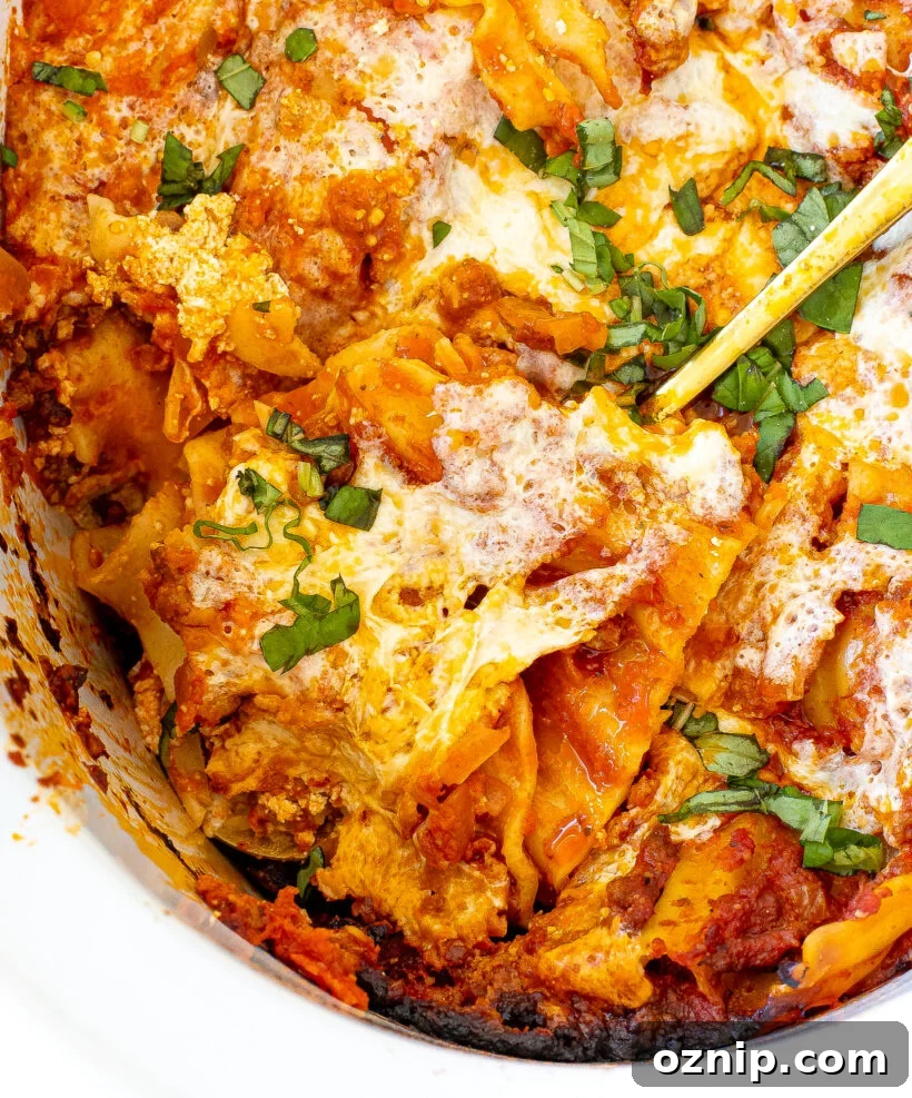 Slow Cooker Lasagna Recipe with Rich Meat Sauce 14 Close up view of a spoon scooping out a serving of lasagna from the slow cooker.