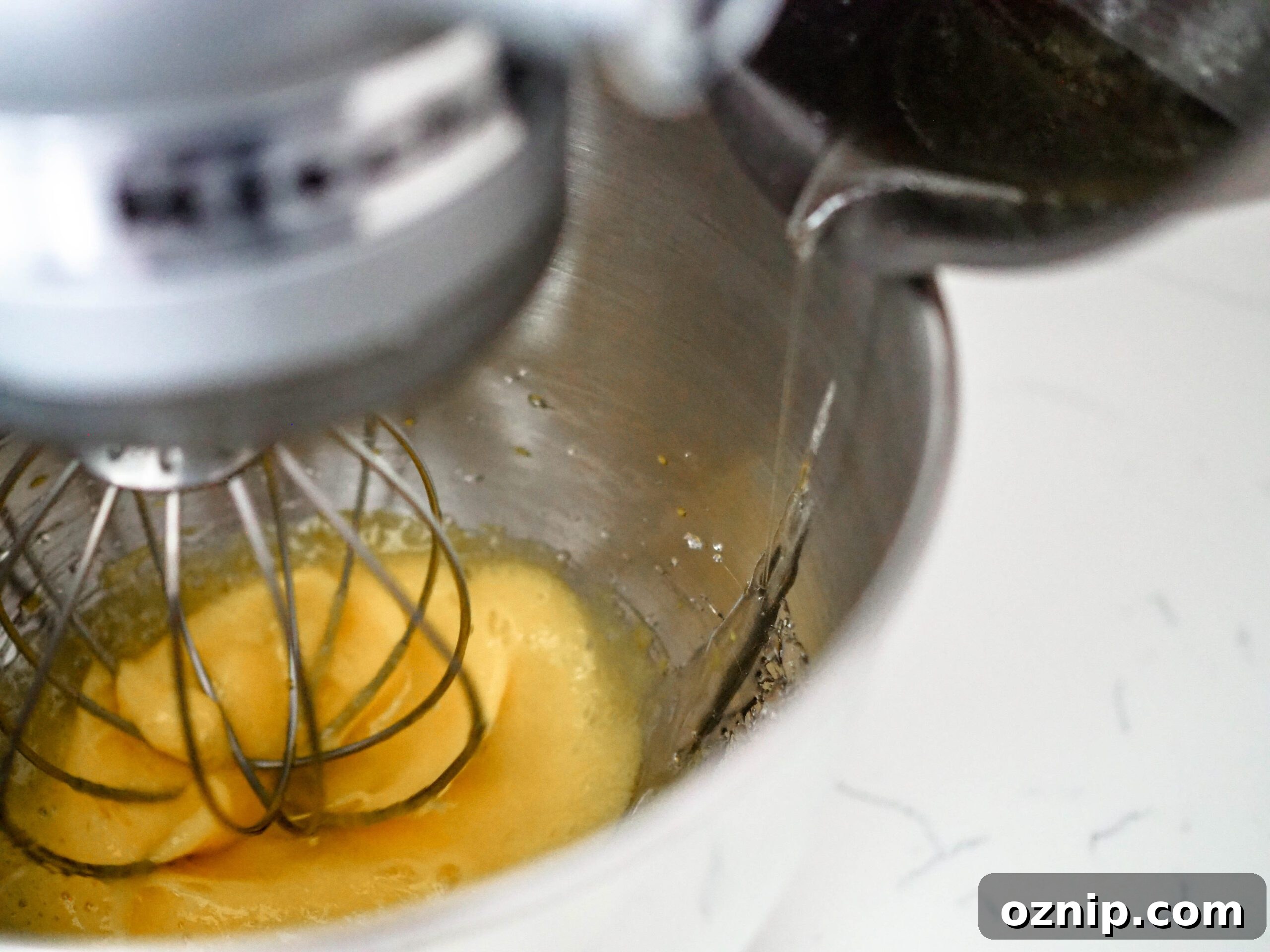 Sugar syrup is poured on the side of the stand mixer bowl instead of directly onto the whisk.