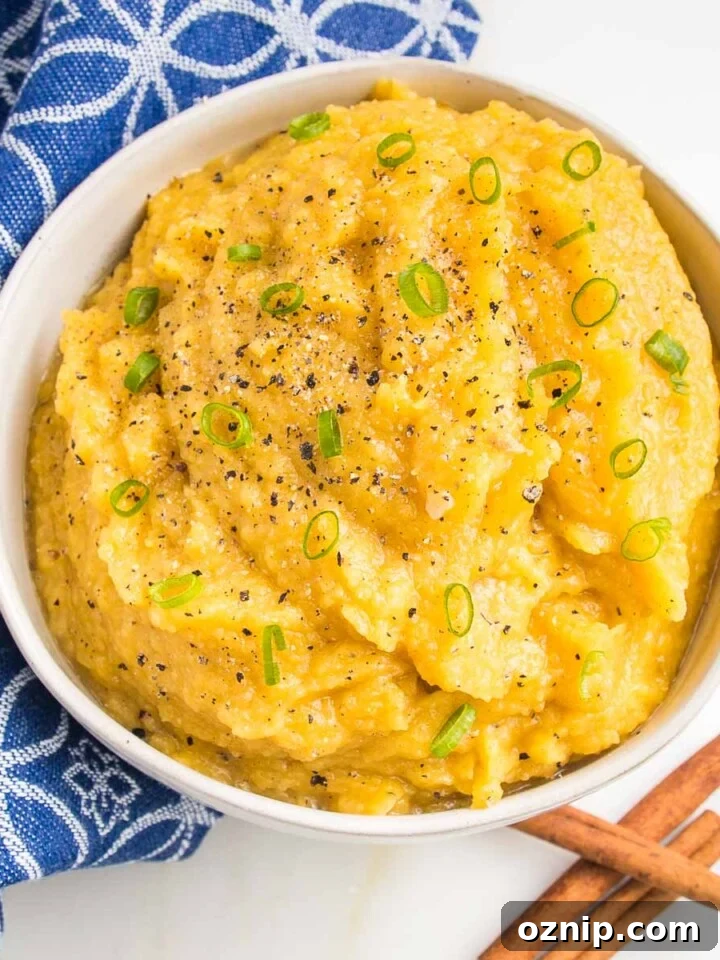 White bowl of mashed acorn squash, garnished with thinly sliced scallions.