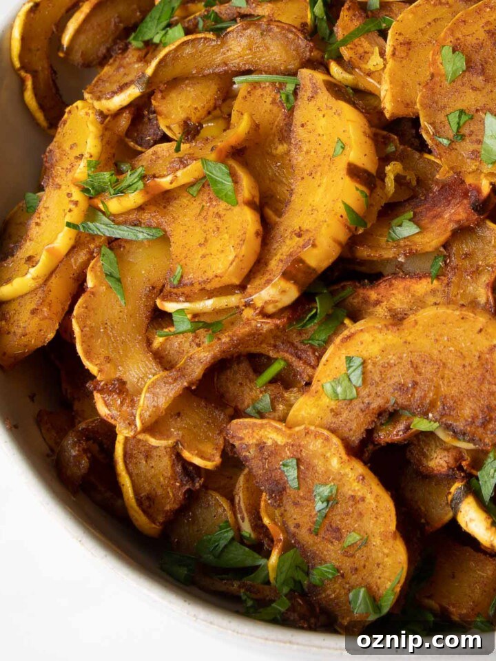 Bowl full of half moon shaped orange delicata squash with fresh green parsley sprinkled on top.