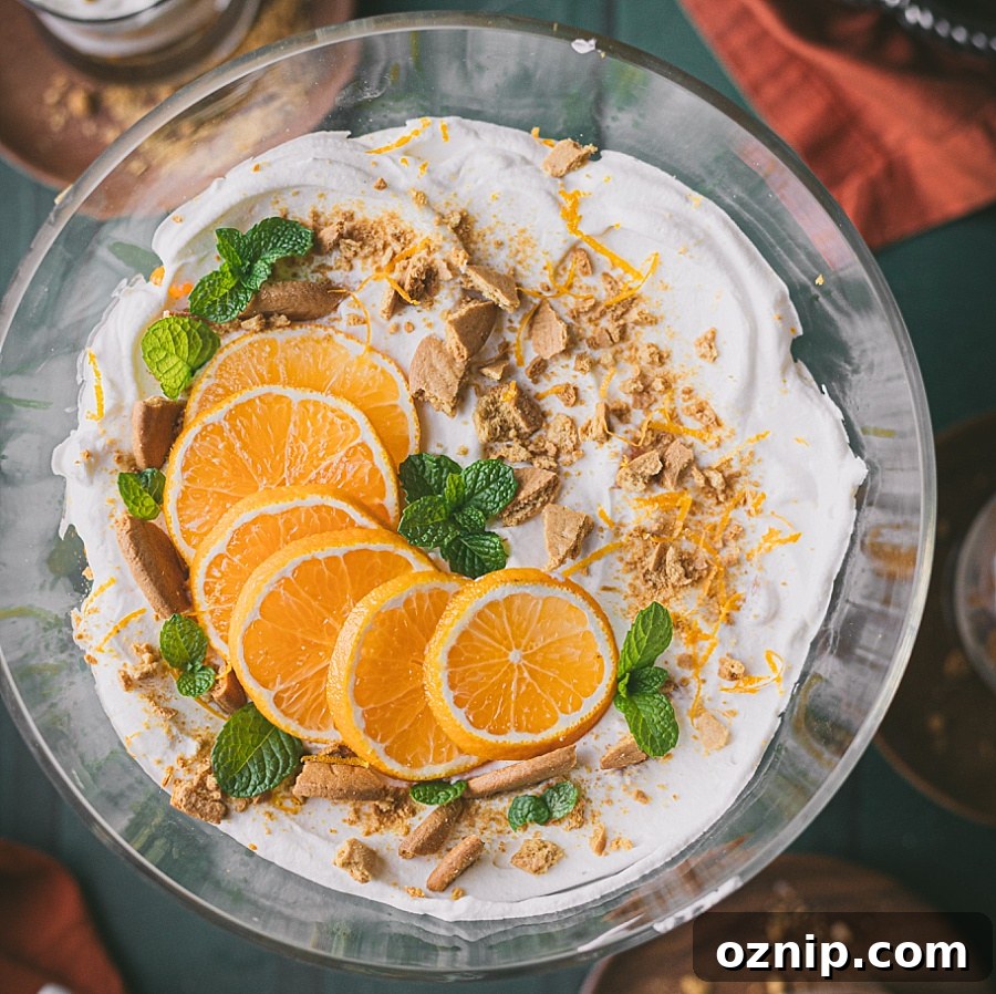 thumbnail overhead shot of ginger mandarin no bake layered dessert. garnished with sliced oranges, crushed gingersnaps, citrus peels, and fresh mint leaves.