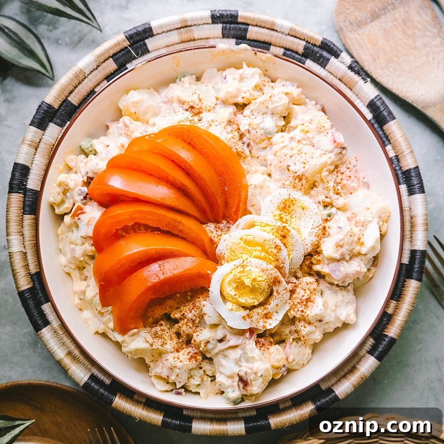 perfect square overhead shot of best potato salad garnished w fresh tomato wedges, hard boiled eggs, and smoked paprika