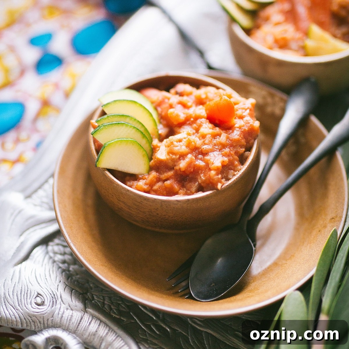 small bowl of red riz au gras garnished with thinly sliced zucchini over traditional ghanaian cloth
