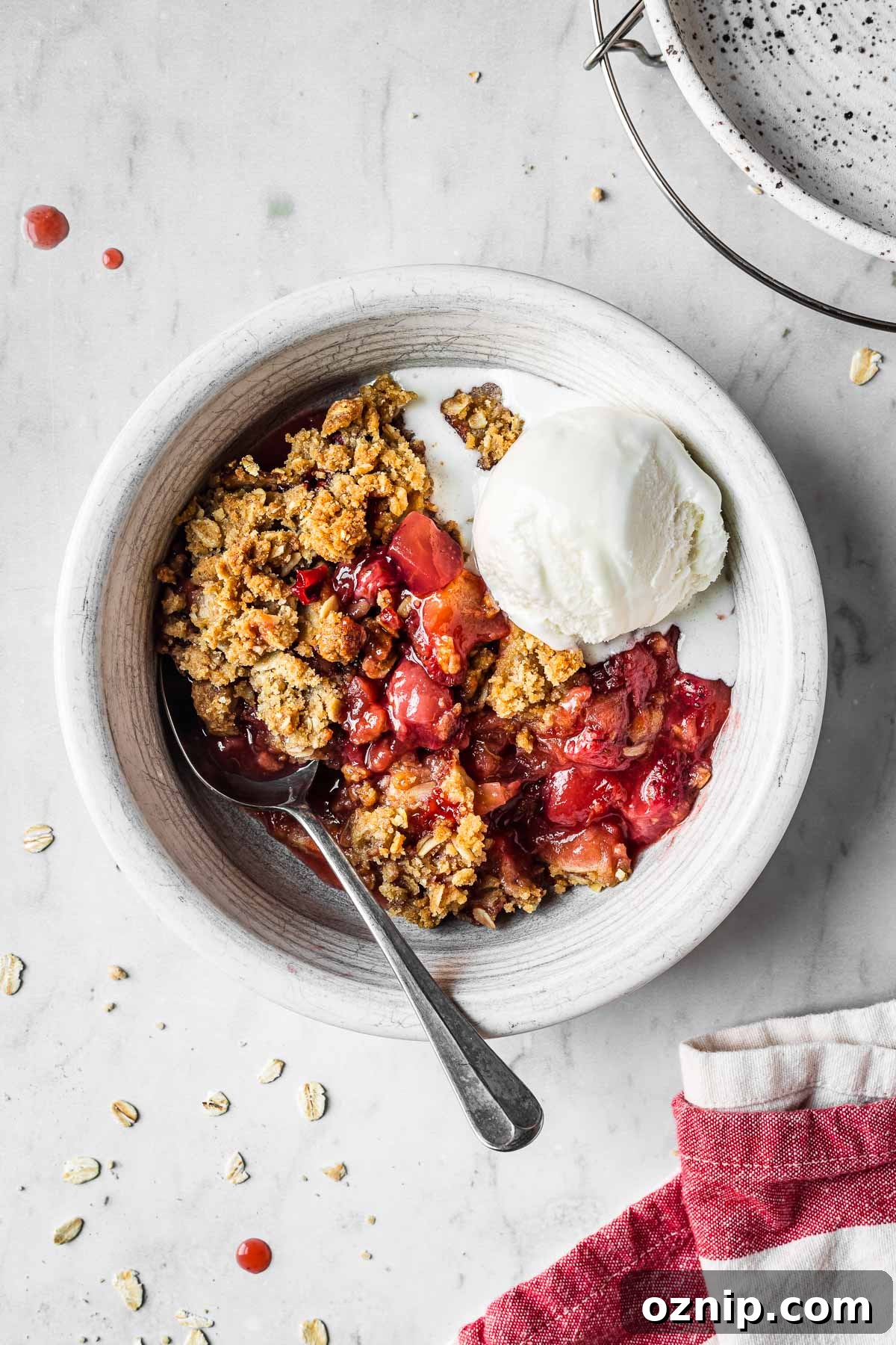 Strawberry Apple Crisp Recipe with Cinnamon Oat Topping 2 A bowl filled with strawberry apple crisp and a scoop of vanilla ice cream.
