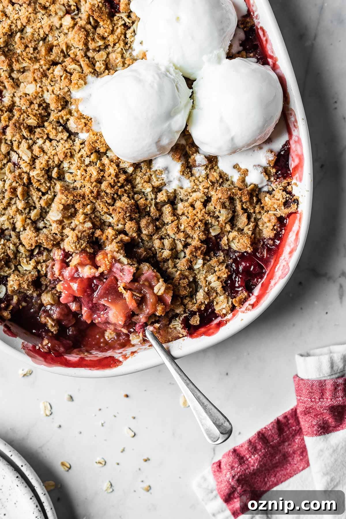 Strawberry Apple Crisp Recipe with Cinnamon Oat Topping 4 A baked strawberry apple crisp with three scoops of ice cream on top.