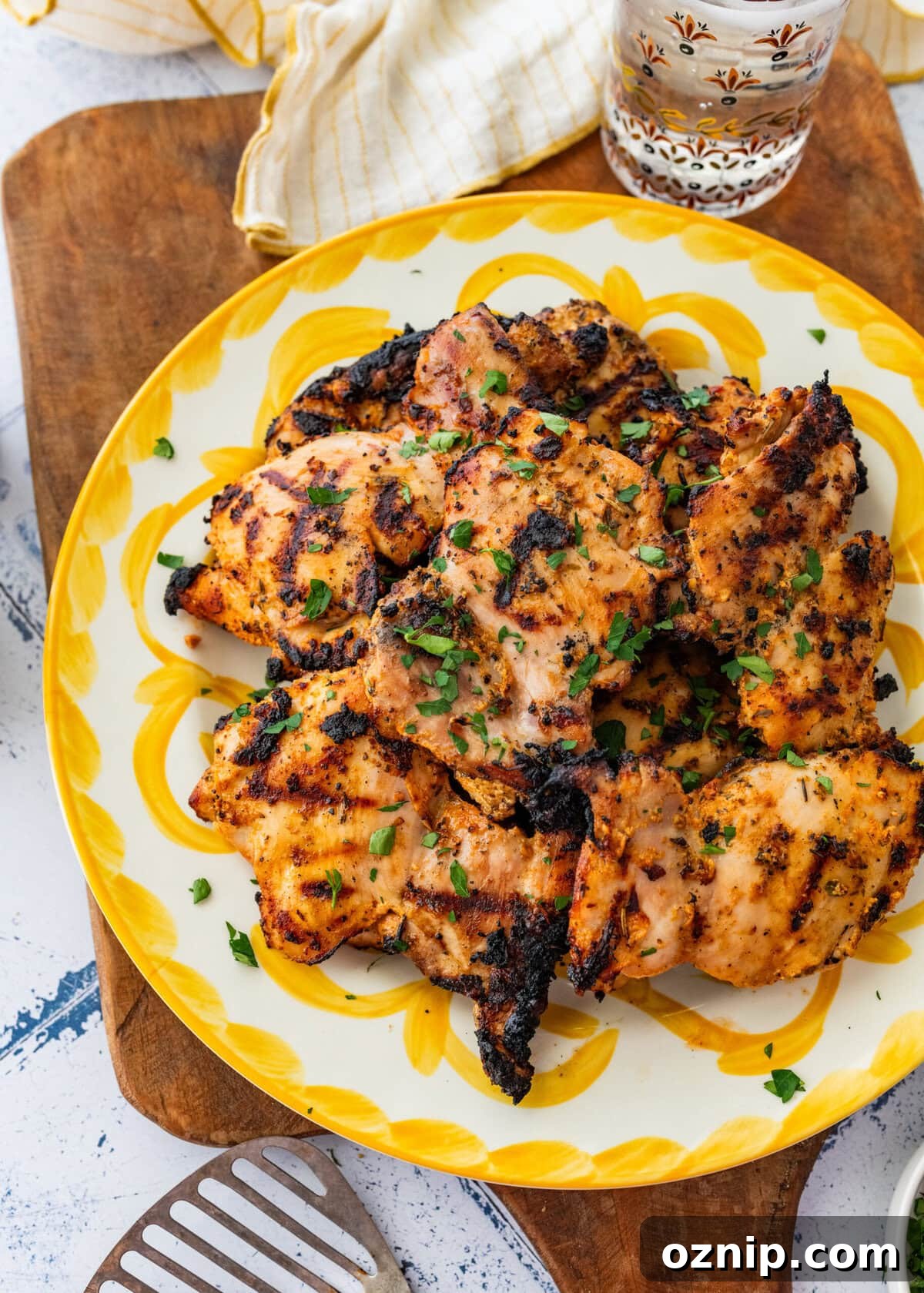 Greek Yogurt Chicken Marinade for Juicy Grilled Chicken 12 Chicken on a serving dish with garnish, and more sides surrounding.
