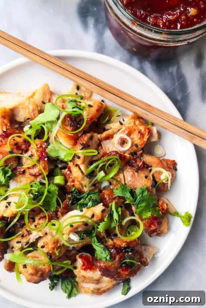 Miso chicken on a white serving plate with spring onion and sesame seeds.