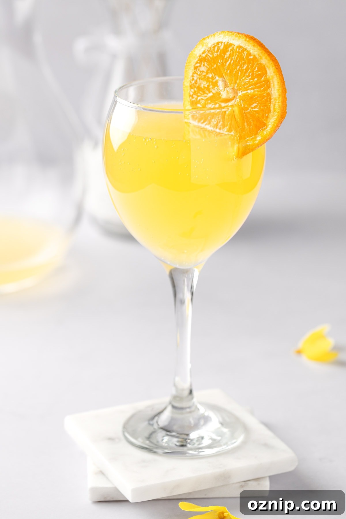 An agua de valencia cocktail on a couple white marble coasters.