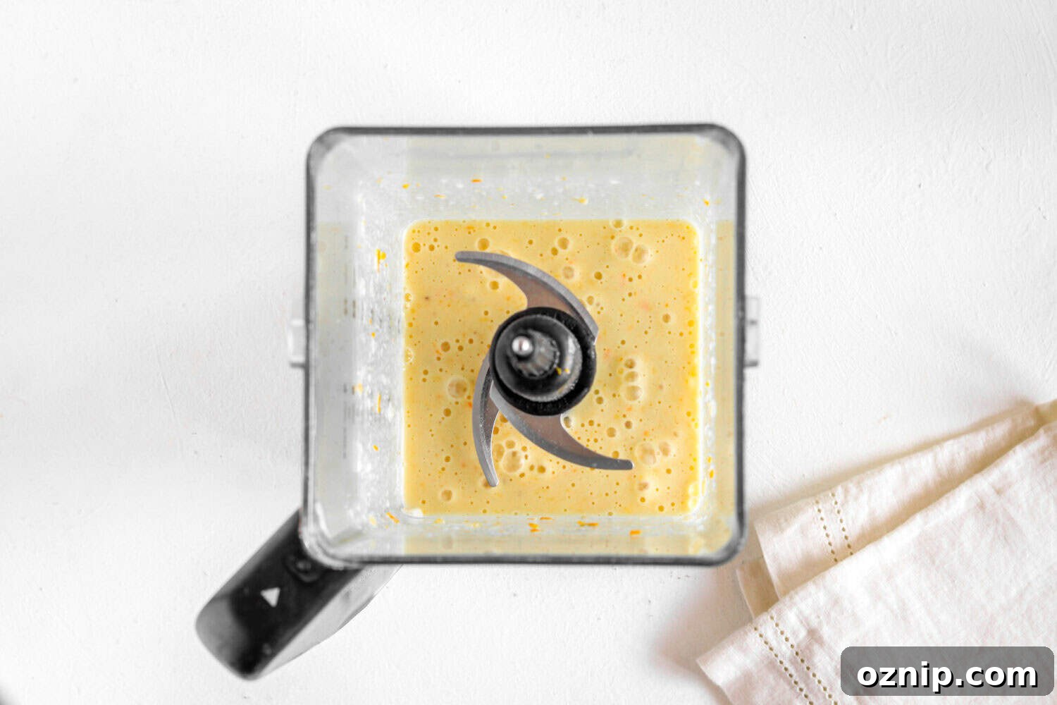 A blended orange fruit smoothie in a blender.